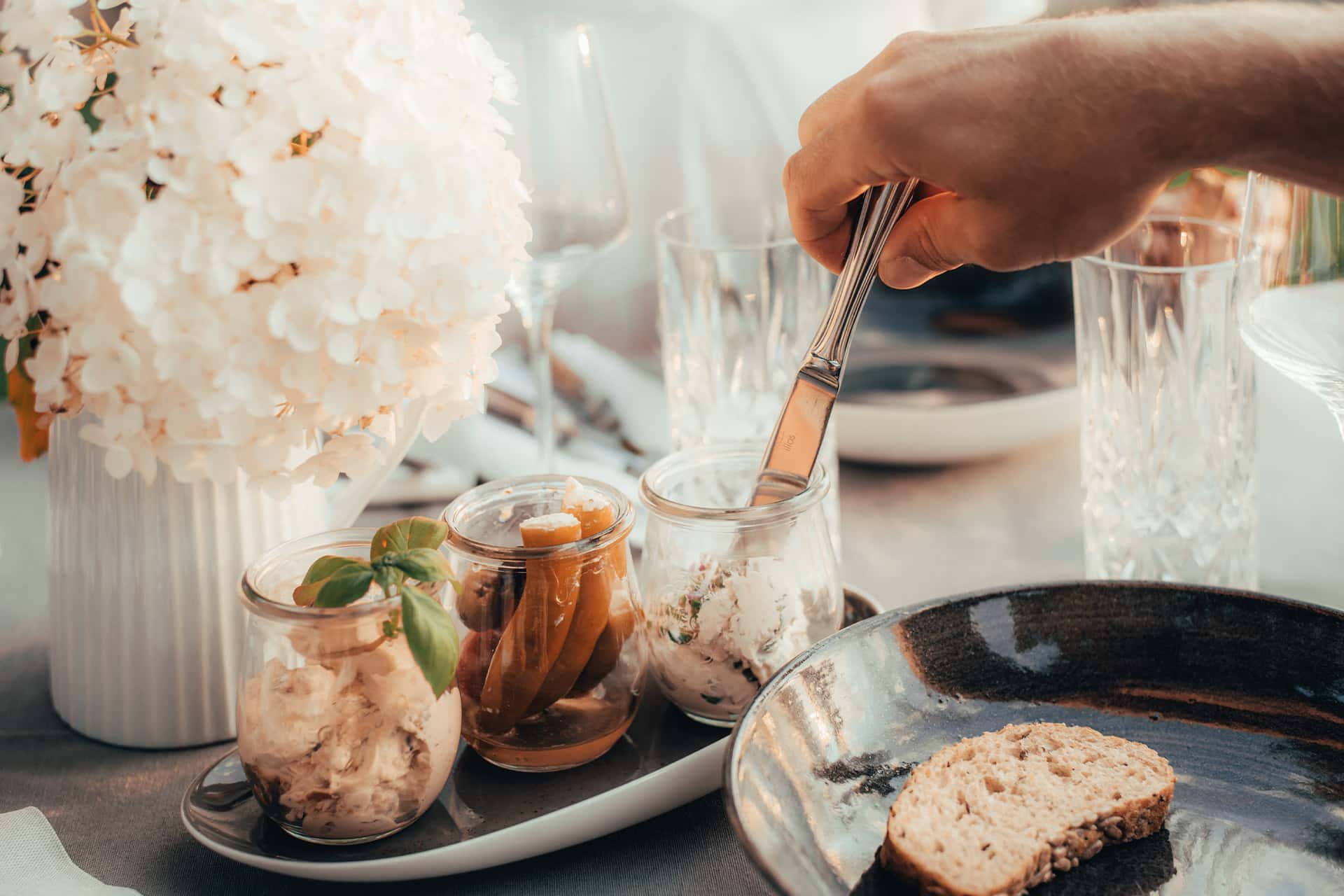 Blick auf einen sommerlich gedeckten Tisch mit frischen Aufstrichen und Antipasti